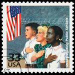 An image of three children standing with their hands on their hearts as they say the Pledge of Allegiance.