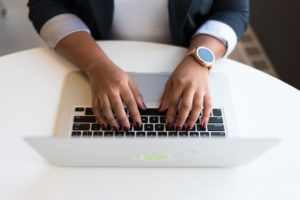A woman sits at a computer typing.