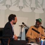 A man interviews a man on stage. 