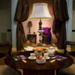 A view of an antique tea table upon which sits tea cups, flowers, and hand fans, inside the Peale building.