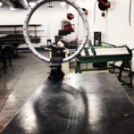 A metal ring rests on a table in a workshop. 