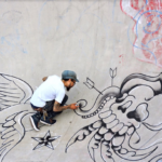 Adam Stab creates graffiti art on a sidewalk.