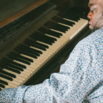 Scott sits at the piano and plays.