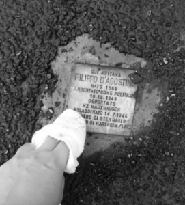 A person bends down and rubs a plaque with a cloth.