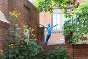 A blue nude statue in the urban garden at the Peale Center.