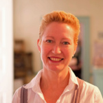 Nancy Proctor wears a white shirt and pearl earrings.