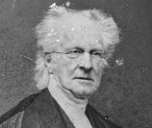 Rembrandt Peale in an early photograph has wispy white hair and a black jacket.