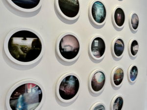 Photographs in circular frames on a white wall in a gallery space.